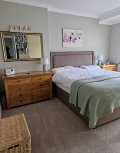 a bedroom with a bed and a dresser and a mirror at Troon Open golf - Private house with garden in central Prestwick in Prestwick