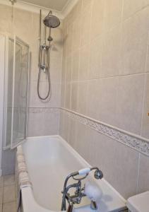 a bathroom with a bath tub and a shower at Troon Open golf - Private house with garden in central Prestwick in Prestwick