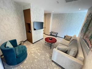 a living room with a couch and a chair and a tv at Arena Grand Hotel in Quba