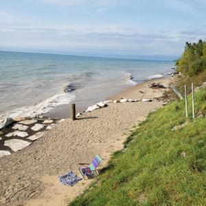 a beach with two lawn chairs and the ocean at Happy Landings - Farmhouse coastal home with tram and stairs to beach access! in South Haven