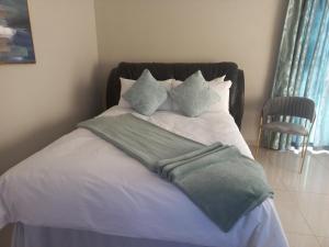 a bed with a green blanket and pillows on it at Achimer guesthouse in Kroonstad