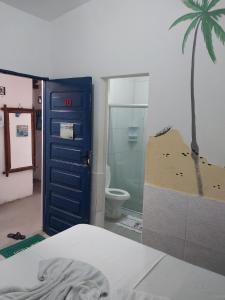 a room with a bed and a bathroom with a palm tree at Pousada Porto Marola in Porto De Galinhas
