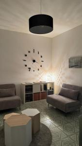 uma sala de estar com dois sofás e um relógio na parede em Green House Calolziocorte em Calolziocorte
