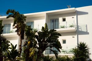 un edificio blanco con palmeras delante en Hostal Mar y Huerta en Es Cana