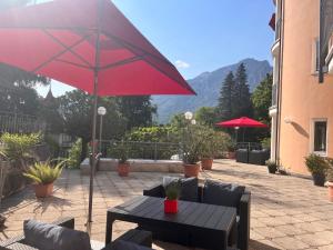 une terrasse avec un parasol rouge et une table dans l'établissement Ferienwohnungen Tivoli, à Bad Reichenhall