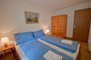 a bedroom with a bed with blue sheets and a cabinet at Haus Bodmen C, Apartment Grünsee in Zermatt