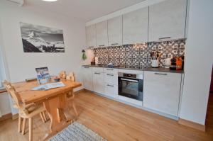 a kitchen with white cabinets and a wooden table at Haus Bodmen C, Apartment Grünsee in Zermatt +7 photos