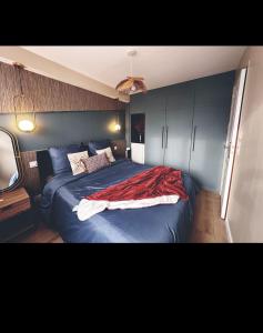 una camera da letto con un letto con una coperta rossa sopra di Appartement Louvres Premium - Roissy CDG a Louvres