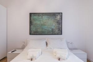 una camera da letto con un letto bianco con un dipinto sul muro di THE FIFTH Properties a Roma
