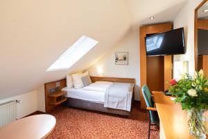 a hotel room with a bed and a flat screen tv at Hotel Garden Bremen in Bremen