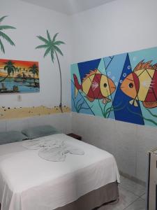 Habitación con cama y pinturas en la pared. en Pousada Porto Marola, en Porto de Galinhas