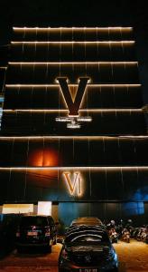 two cars parked in front of a building with avy sign at VI Hotel Bandung in Bandung