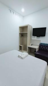 a bedroom with a bed and a couch and a tv at VI Hotel Bandung in Bandung