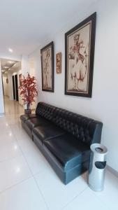 a black leather couch in a room with pictures on the wall at VI Hotel Bandung in Bandung