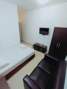 um quarto com uma cama e duas cadeiras e uma televisão em VI Hotel Bandung em Bandung