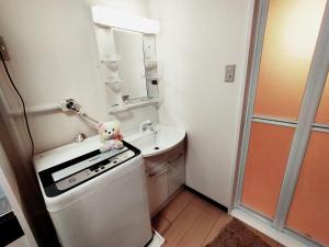 a small kitchen with a teddy bear sitting on top of a refrigerator at SECRET BASE Station Side in Osaka +26 photos