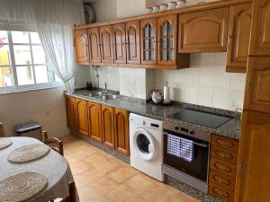 a kitchen with wooden cabinets and a washer and dryer at Piso O Percebe in Muxia