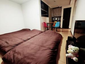 un osito de peluche sentado en una cama en un dormitorio en SECRET BASE Station Side, en Osaka