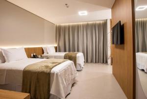 um quarto de hotel com duas camas e uma televisão em Amazon Aeroporto Hotel em Cuiabá