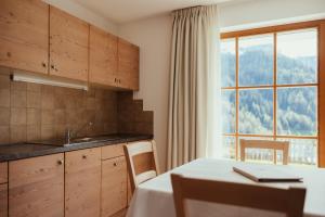 cocina con mesa y ventana grande en Refugium LaFlu Apartments, en Corvara in Badia