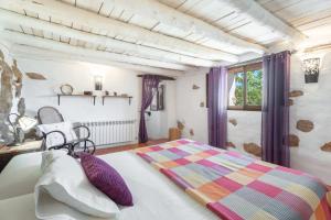 1 dormitorio con 1 cama con cortinas moradas y ventana en El Cup, en La Torre d'En Besora