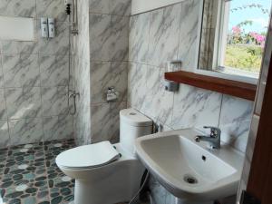 een badkamer met een wit toilet en een wastafel bij Sambag Hideaway Bungalows in Moalboal