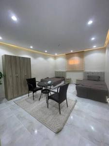 sala de estar con mesa, sillas y cama en شقة ريم الوجة, en Al Wajh