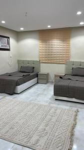 two beds in a room with a rug at شقة ريم الوجة in Al Wajh