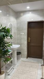 baño con lavabo y puerta marrón en شقة ريم الوجة, en Al Wajh