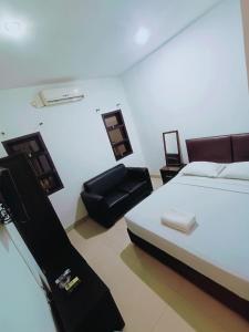 um quarto com uma cama e uma cadeira preta em VI Hotel Bandung em Bandung