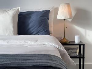 a bed with a blue pillow and a table with a lamp at Bright & Spacious Flat In London in Croydon