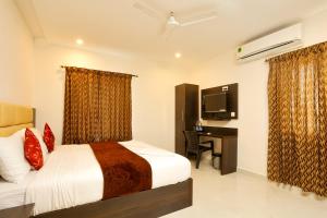 a bedroom with a bed and a desk and a television at Rameswaram Harish Palace in Rāmeswaram