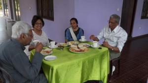 un grupo de personas sentadas alrededor de una mesa comiendo comida en Tharindu Villa en Dankotuwa
