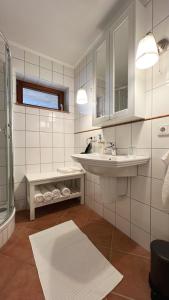La salle de bains blanche est pourvue d'un lavabo et d'un miroir. dans l'établissement Galeriewohnung mit Blick in den Schwarzwald, à Todtmoos