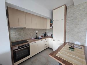 une cuisine avec des armoires blanches et une table en bois dans l'établissement Sunčani apartman, à Nikšić 6 autres photos