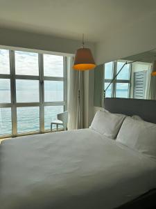 a bedroom with a large white bed with windows at Hotel Miramare - Adults Only in Trieste