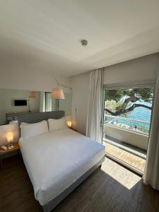 a bedroom with a bed and a view of a beach at Hotel Miramare - Adults Only in Trieste