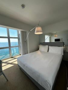 a bedroom with a large bed and a large window at Hotel Miramare - Adults Only in Trieste