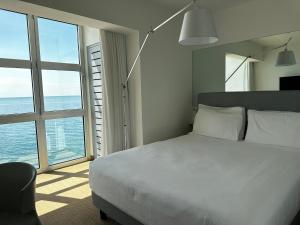 a bedroom with a white bed and a large window at Hotel Miramare - Adults Only in Trieste