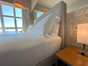 a bedroom with a bed with white pillows and a desk at Hotel Miramare - Adults Only in Trieste