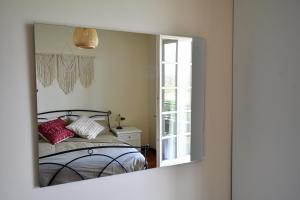 een spiegel die een slaapkamer met een bed en een raam weerspiegelt bij Angolo Paradiso - Casa vacanze sui campi da golf in Fubine