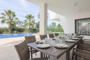 une salle à manger avec une table et des chaises et une piscine dans l'établissement Villa Moroz - BY BEDZY, à Almancil