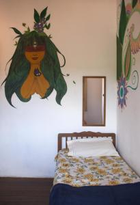 a bedroom with a bed with a painting on the wall at MangaMel Hostel in Lençóis
