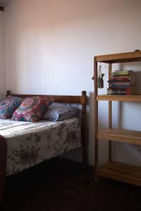 a bedroom with a bed and a shelf with books at MangaMel Hostel in Lençóis