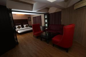 Una habitación con una cama y sillas rojas y un dormitorio en Quaint Suites Hotel & Banquet en Bombay