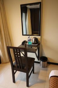 a desk with a chair in a room with a mirror at Quaint Suites Hotel & Banquet in Mumbai