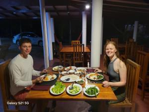 un hombre y una mujer sentados en una mesa con platos de comida en Hotel Tree Garden Wilpaththu Nochchiyagma Anuradhapura, en Nochchiyagama