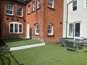 un patio con tavolo e sedie di fronte a un edificio in mattoni di Relaxing 1 bedroom garden flat. a Brentwood