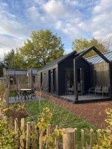 a black building with a picnic table in a yard at Knus I Tiny house op de Veluwe in Epe