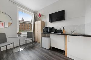a kitchen with a sink and a counter with a table at Archway Station Studios - Double bed in London